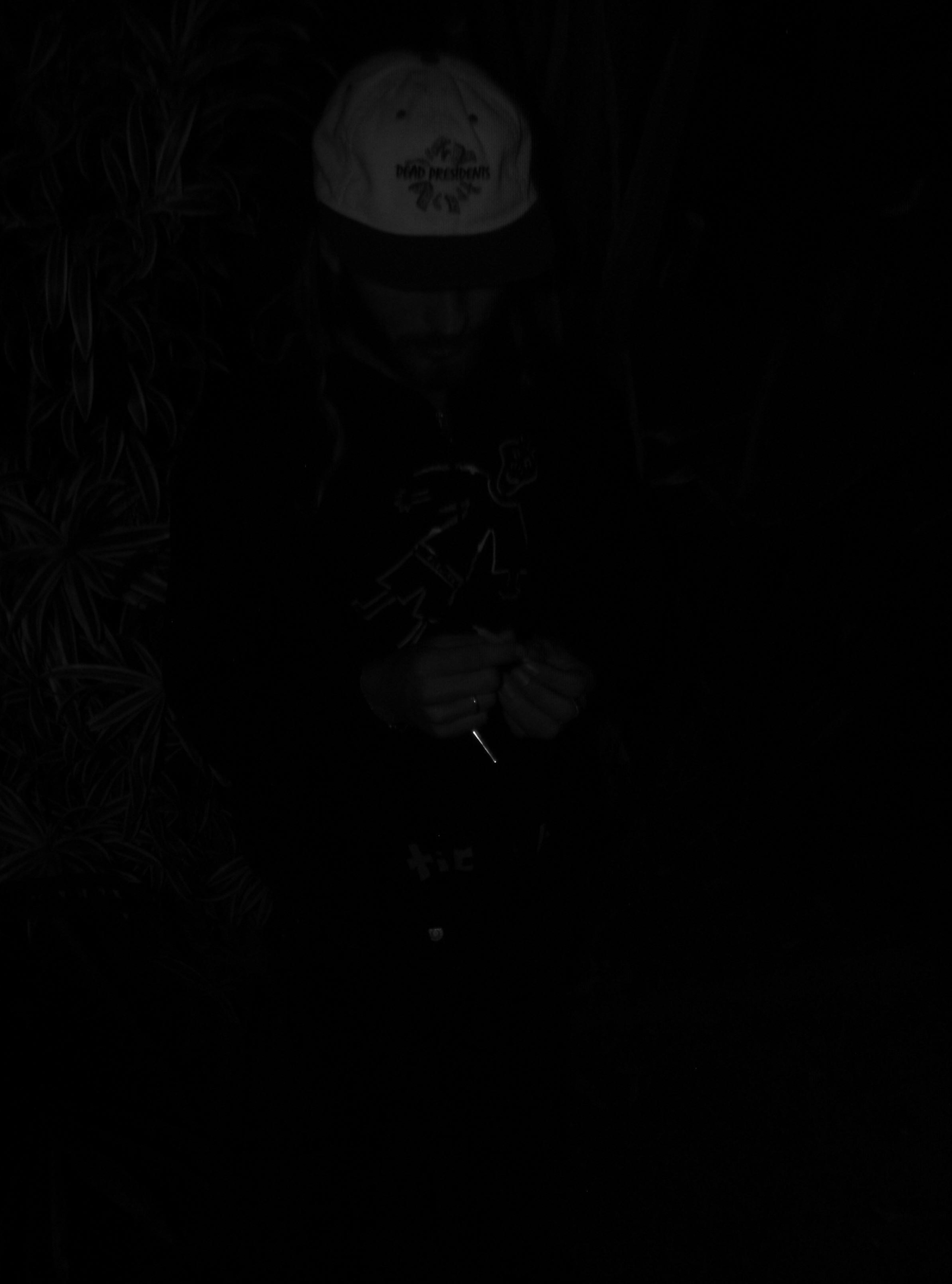 A person standing in the dark holding a cell phone.