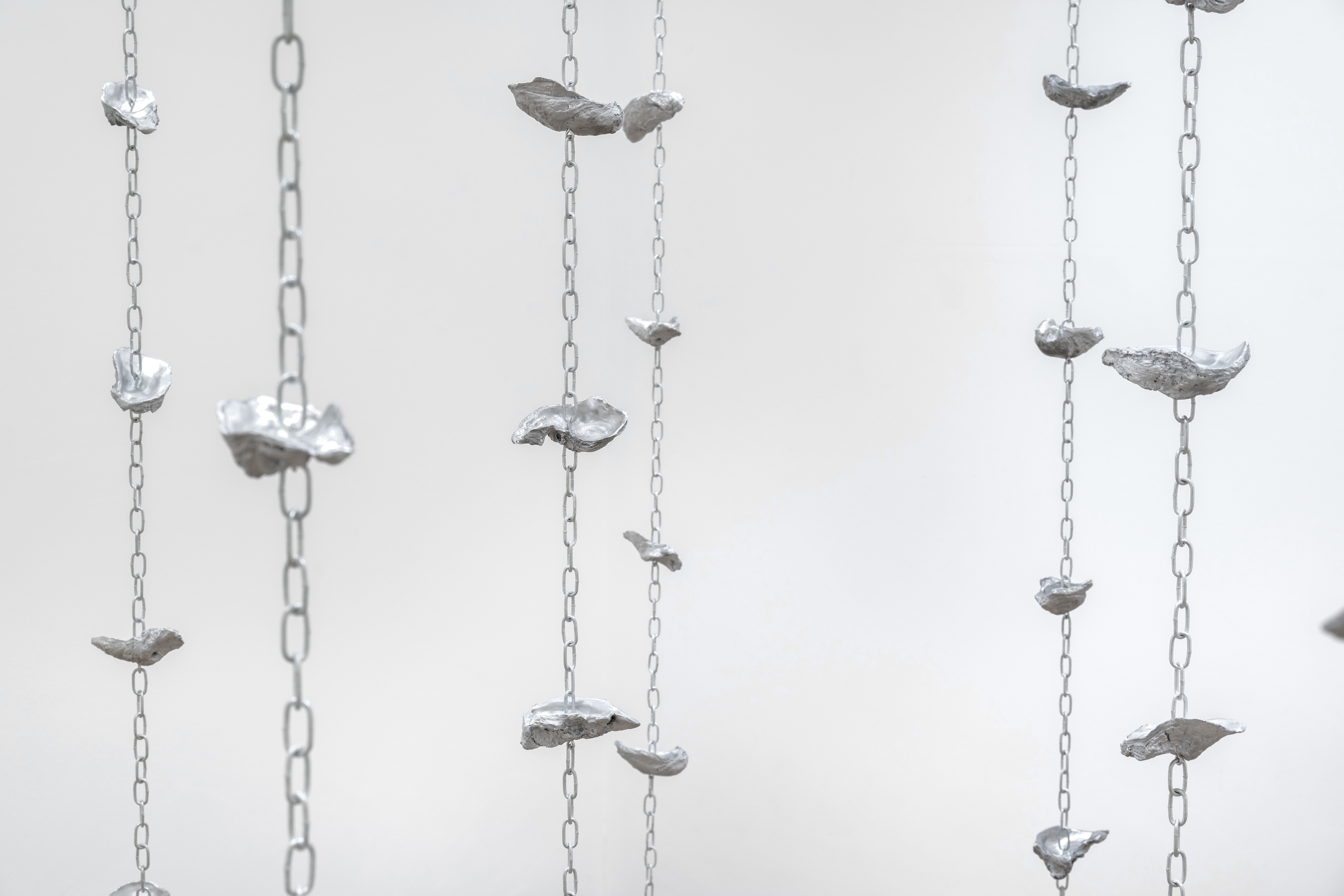Nicole Coson, Some place, within here (2024). Aluminum cast oyster, shells and chains. Dimensions variable. Courtesy of the artist and Silverlens Galleries.