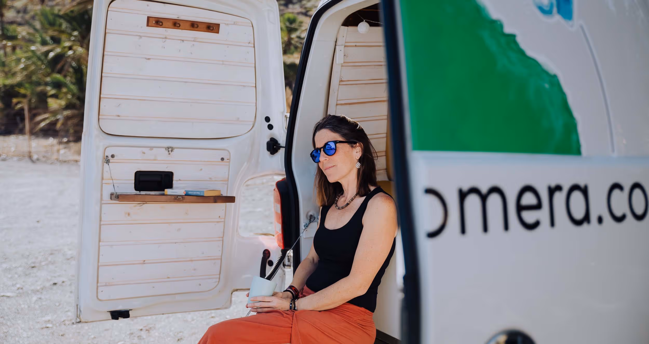 Camper Majona con una persona sentada junto a la puerta lateral.