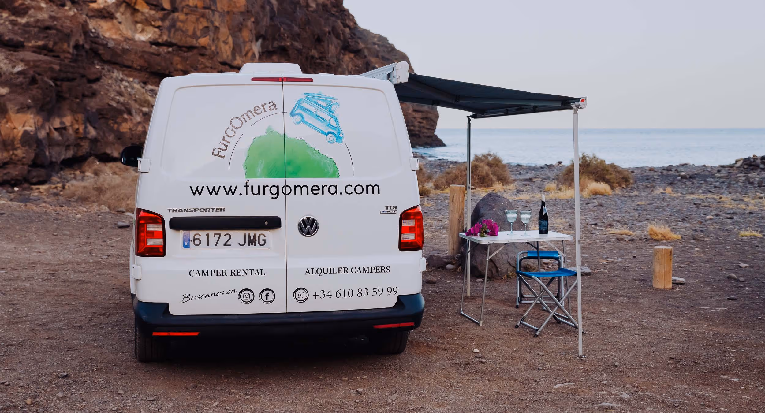 Vista trasera de la camper Majona con mesa y sillas de camping.