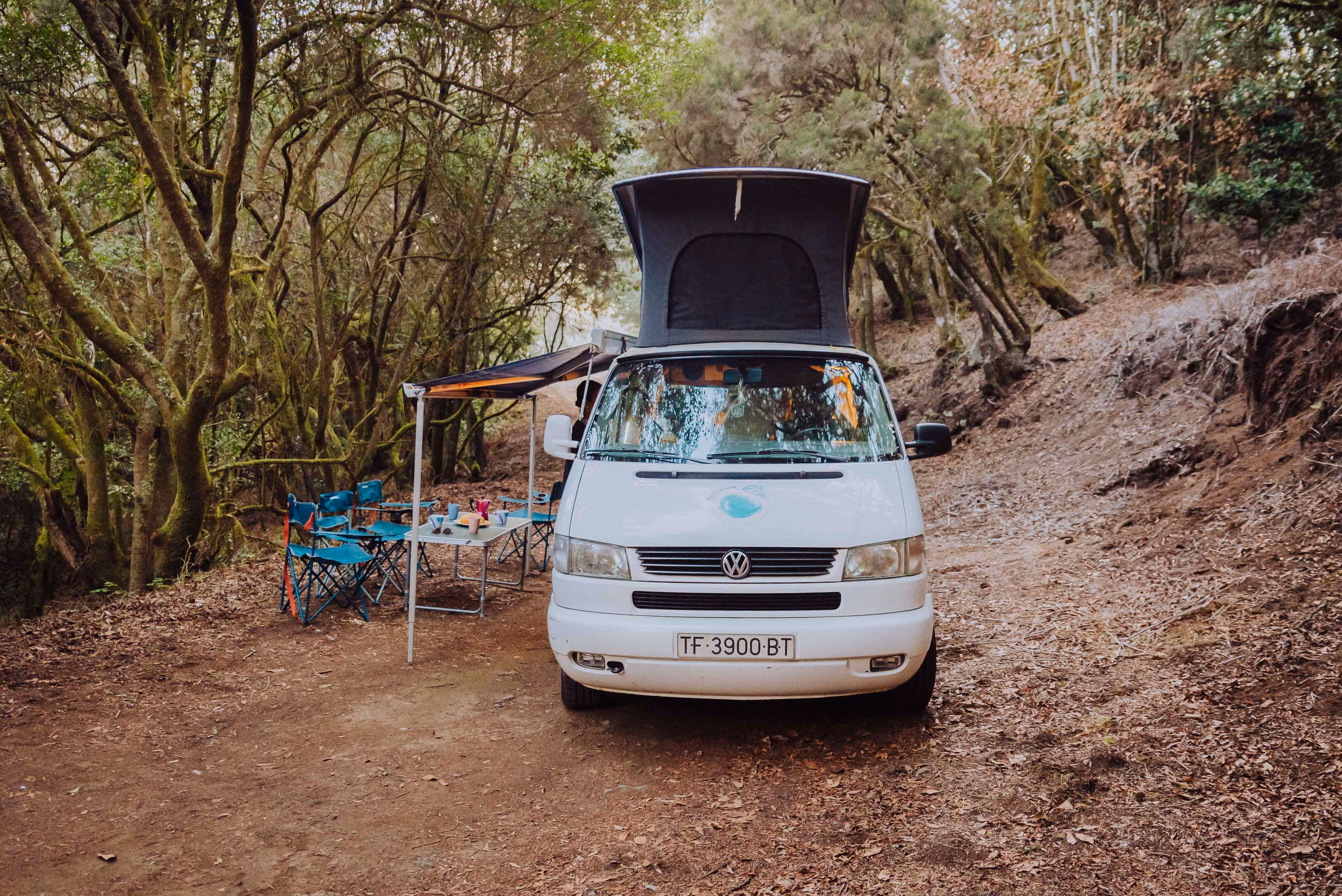 Camper Agana aparcada en un área de acampada entre árboles.