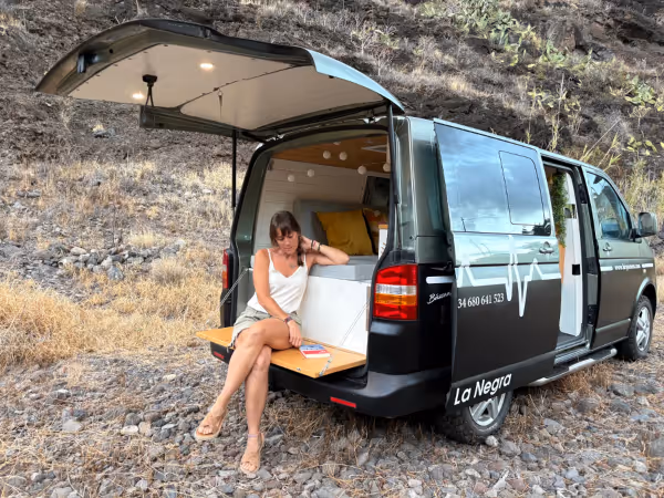 Camper Avalo con las puertas traseras abiertas, con una persona sentada en el portón.