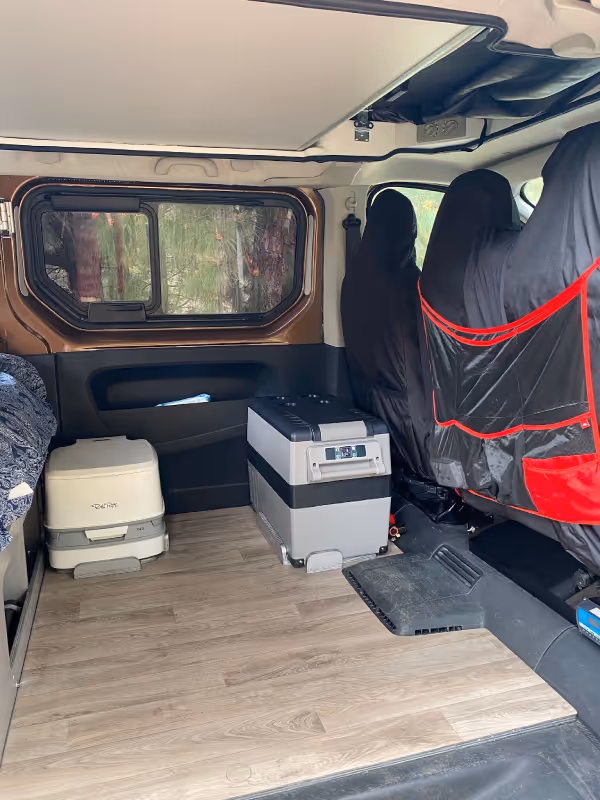 Interior de la camper Arguamul con zona de asiento y espacio de almacenaje.