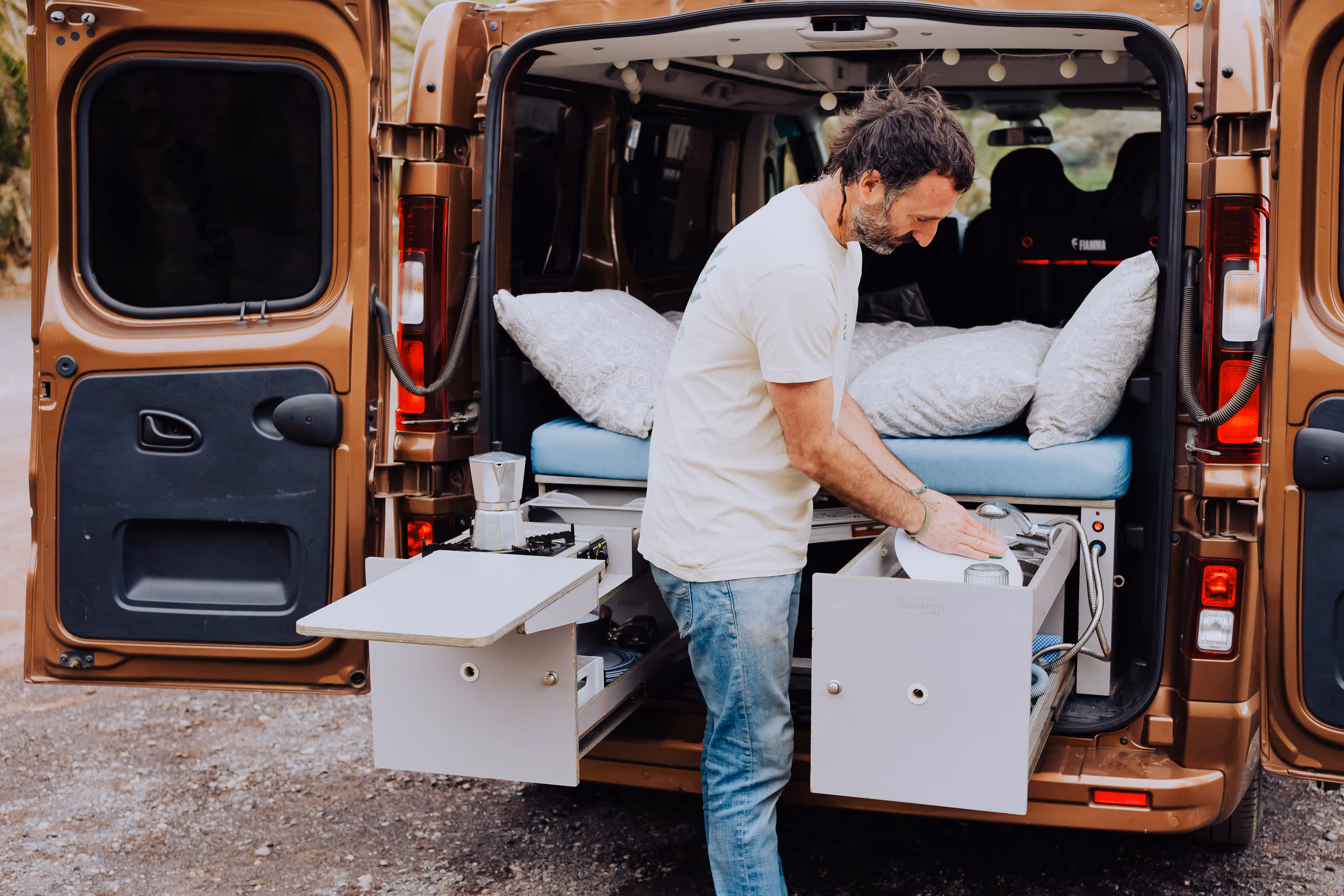 Interior trasero de la camper Arguamul con cama y módulos de cocina