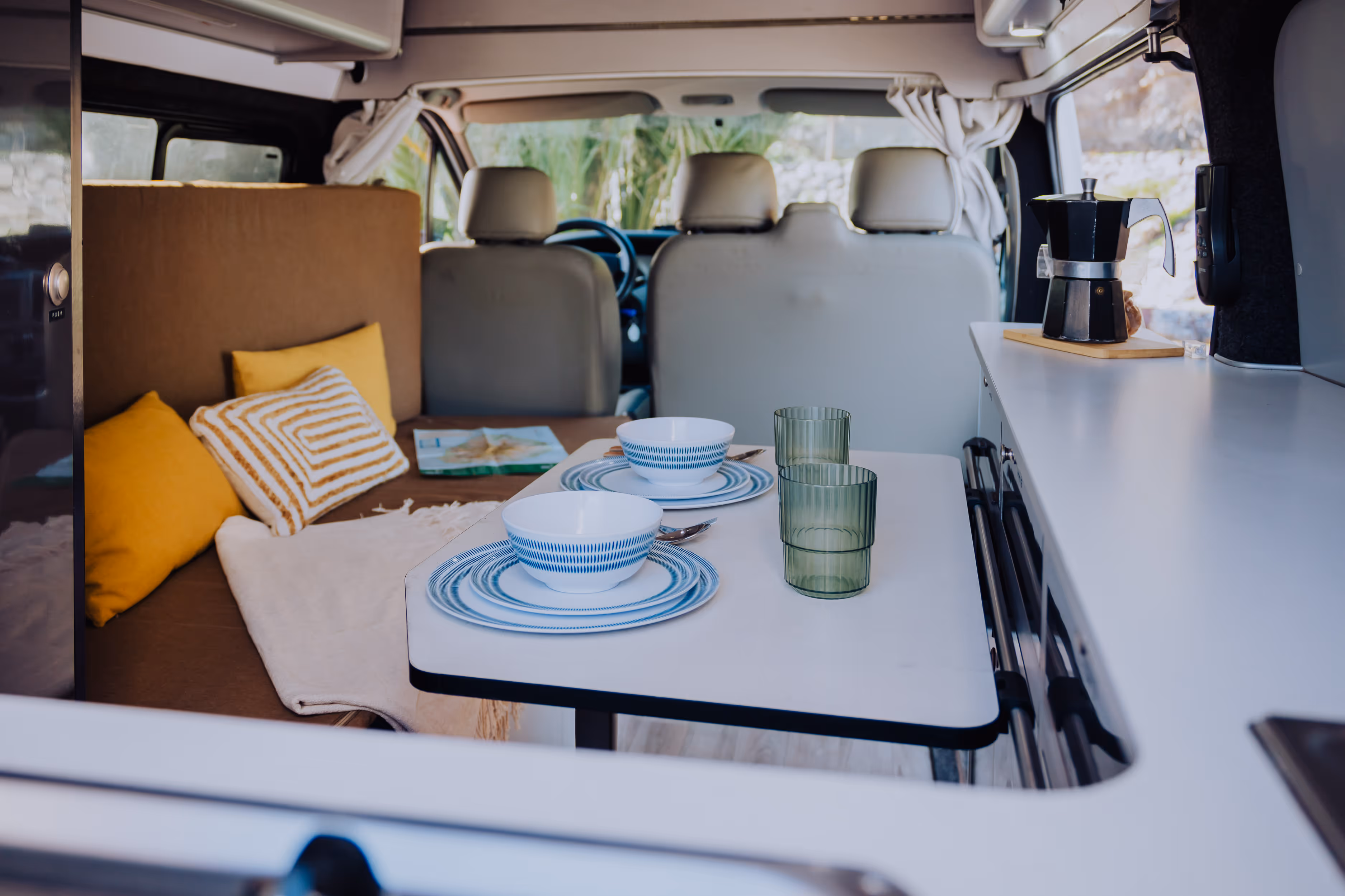 Interior de la camper Avalo con mesa, vajilla y zona de comedor