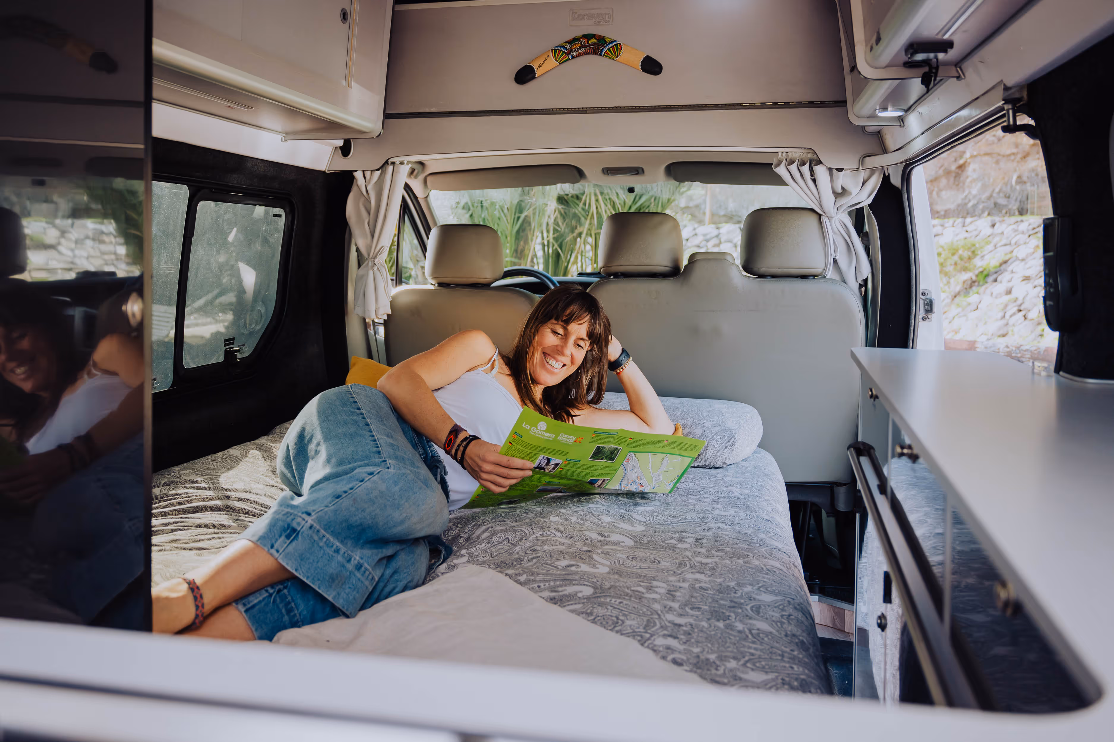 Viajera descansando en la cama de la camper Avalo con mapa turístico