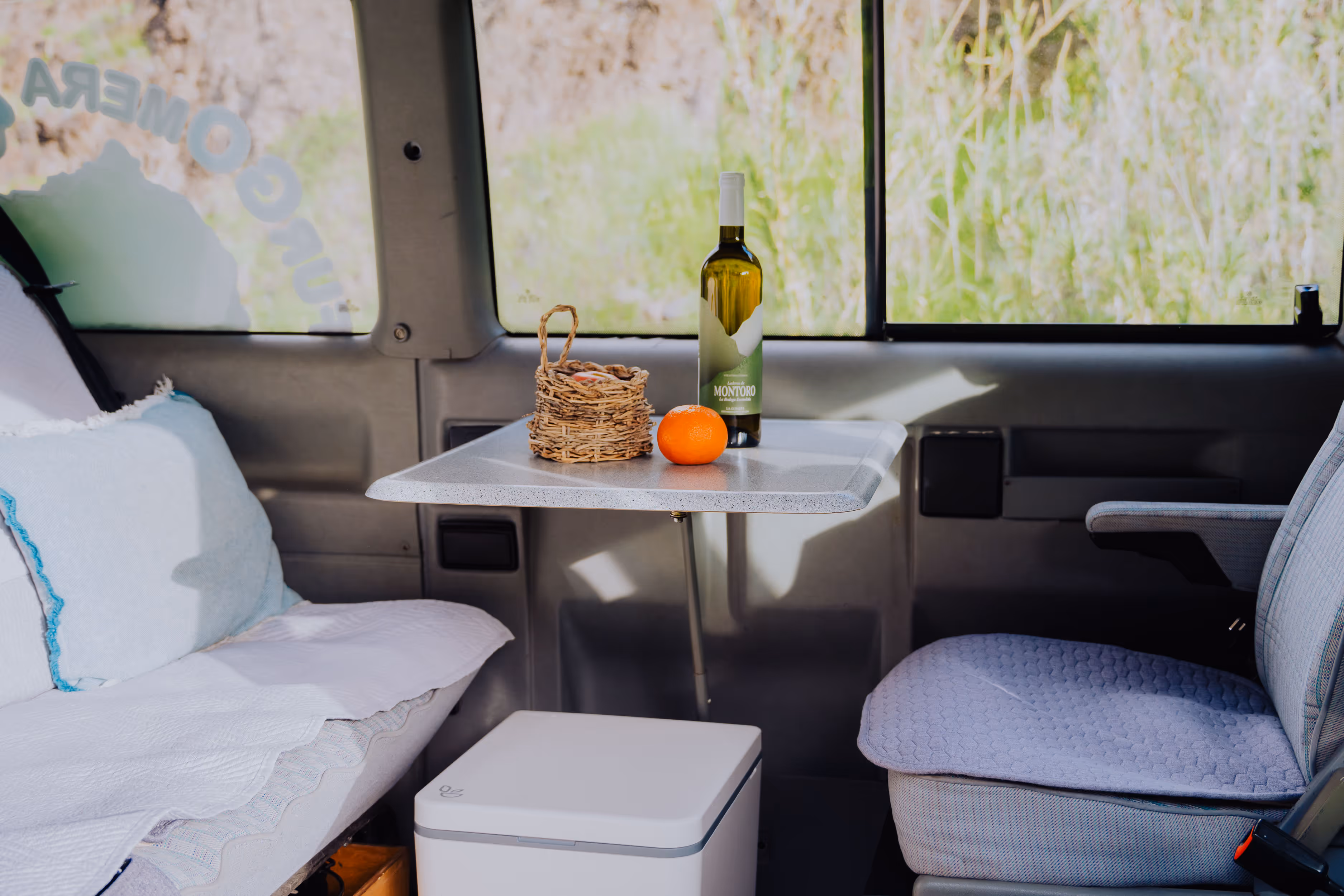 Interior de la camper Hipalan con mesa, nevera y zona de descanso