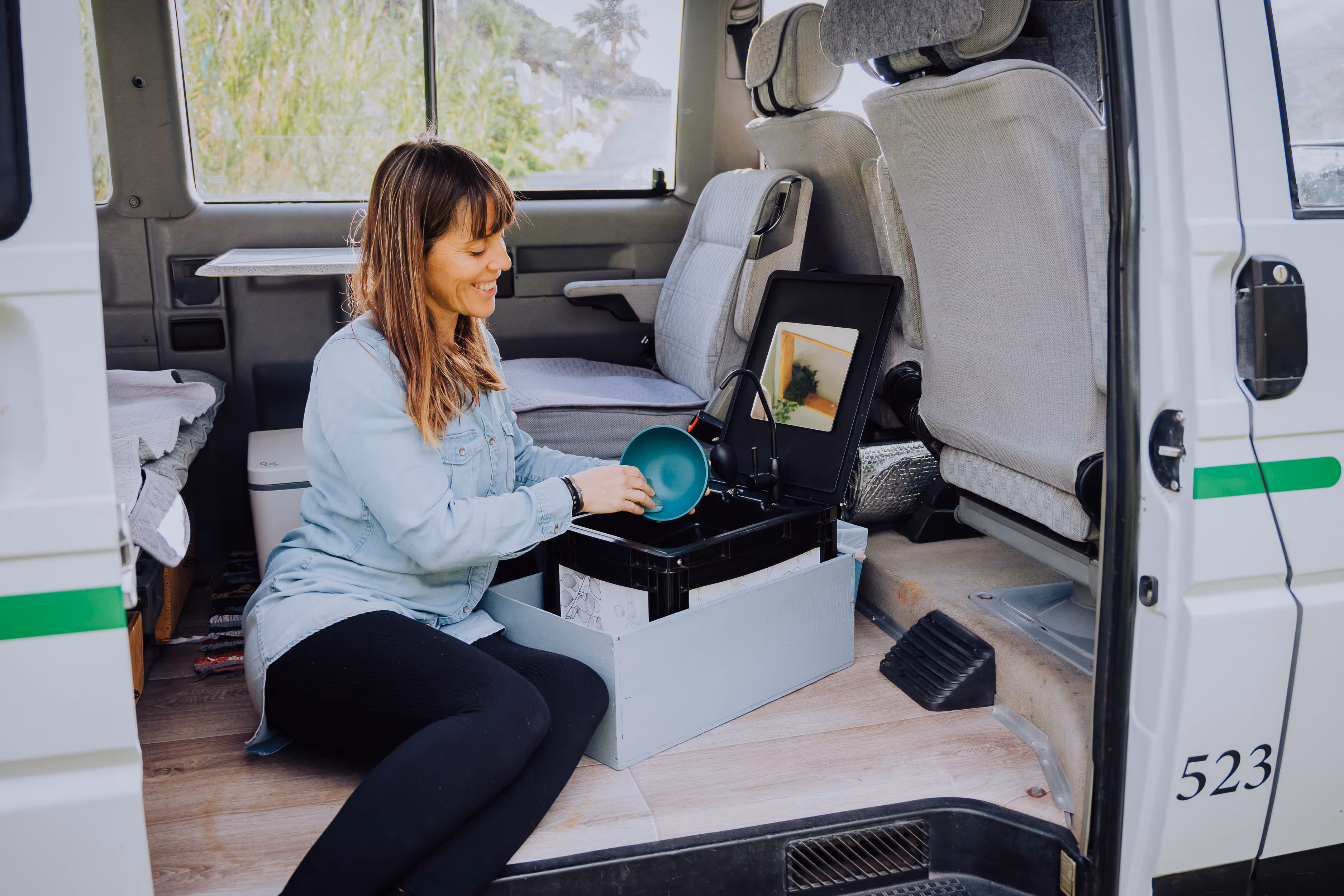 Viajera usando el fregadero portátil en el interior de la camper Hipalan