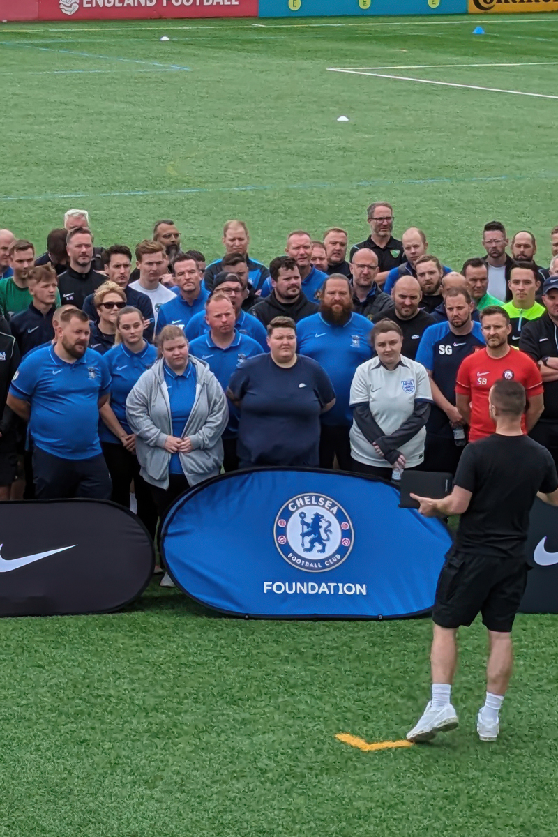 A group of people a listening to a coach on a football field