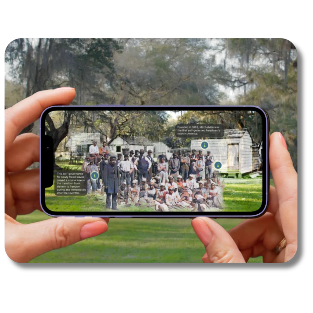 Guru Museum App on a phone showing a historic AR photo overlay of freed slaves in front of wooden houses in a grassy area.