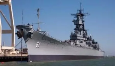 The Battleship IOWA, hull number 61, moored bow-first at its pier under a clear blue sky, the museum ship behind this ROI case study.