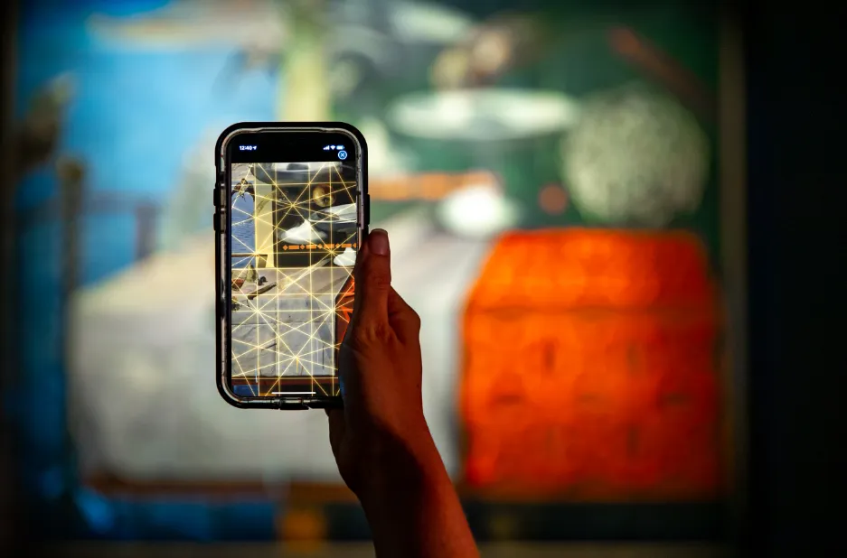 Hand holding a phone in front of a large Dali painting while the screen overlays a glowing gold geometric grid on the artwork.