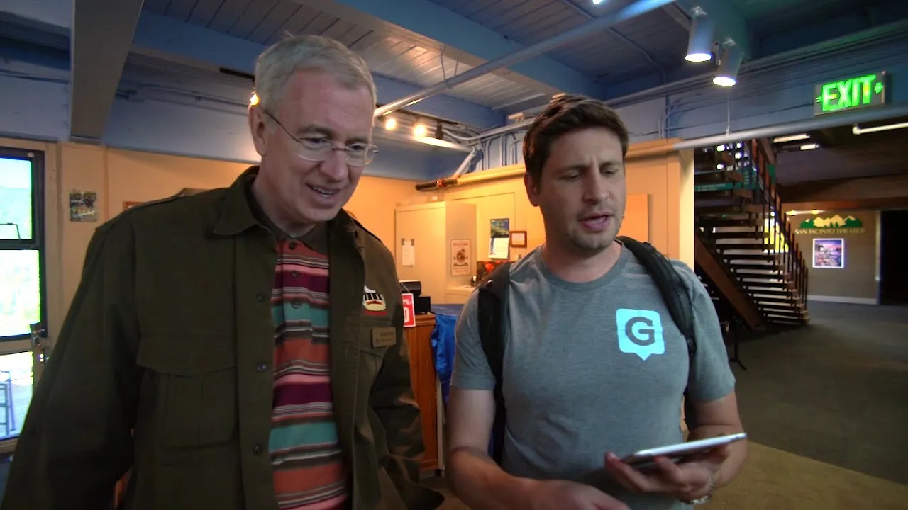 Palm Springs Aerial Tramway staff member walking through the lobby with a Guru team member in a Guru logo shirt who is holding a tablet.