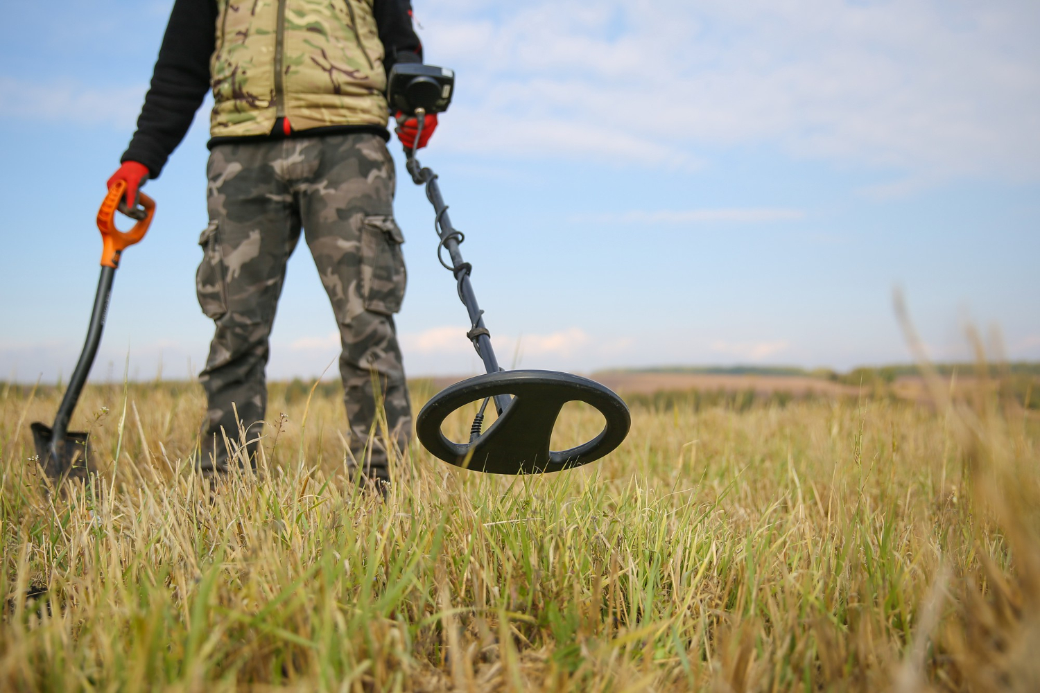 Caçador de tesouros com detector de metais e uma pá no campo