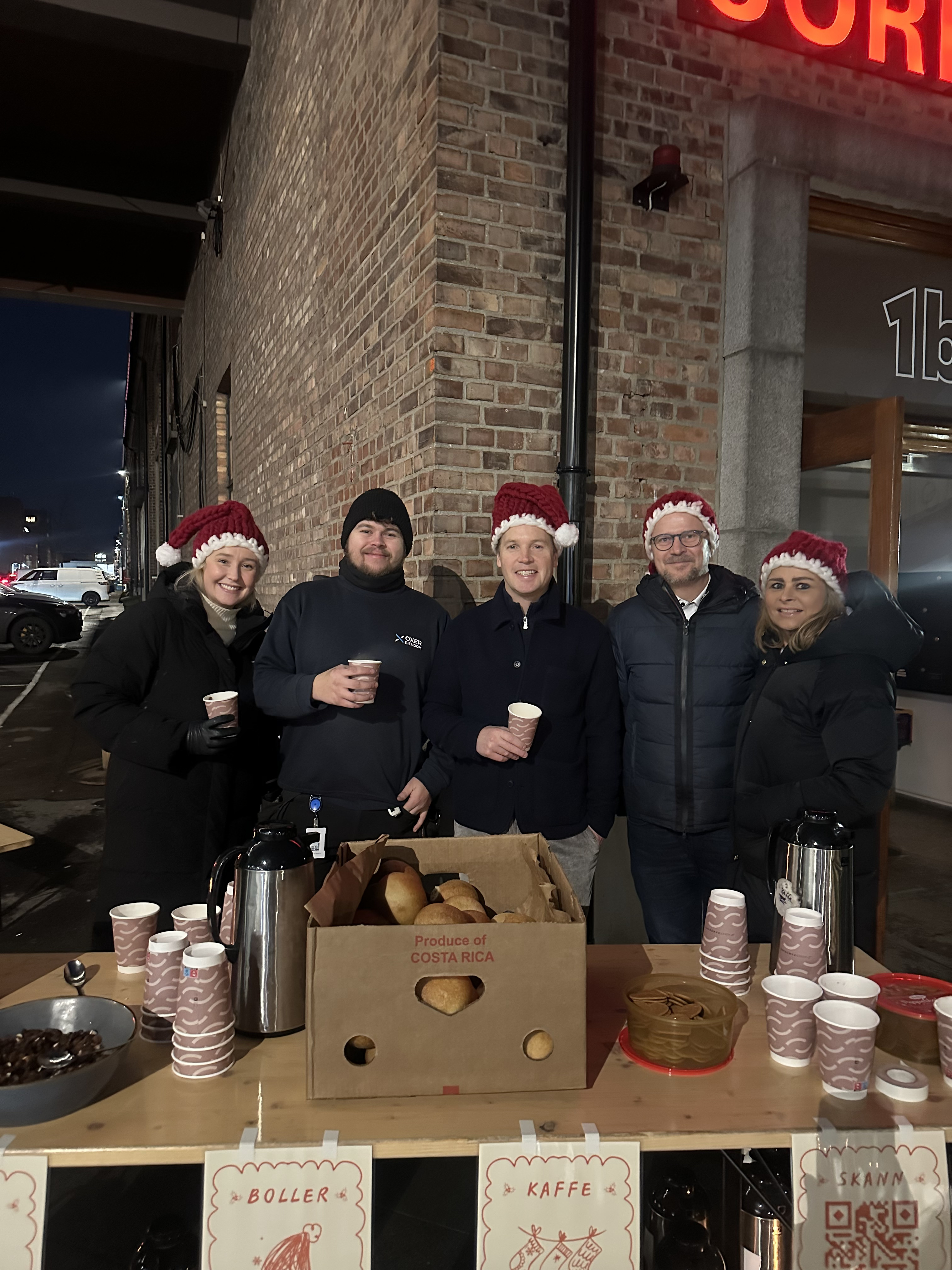 Gjengen med nisseluer bak bordet med gløgg, kaffe og boller
