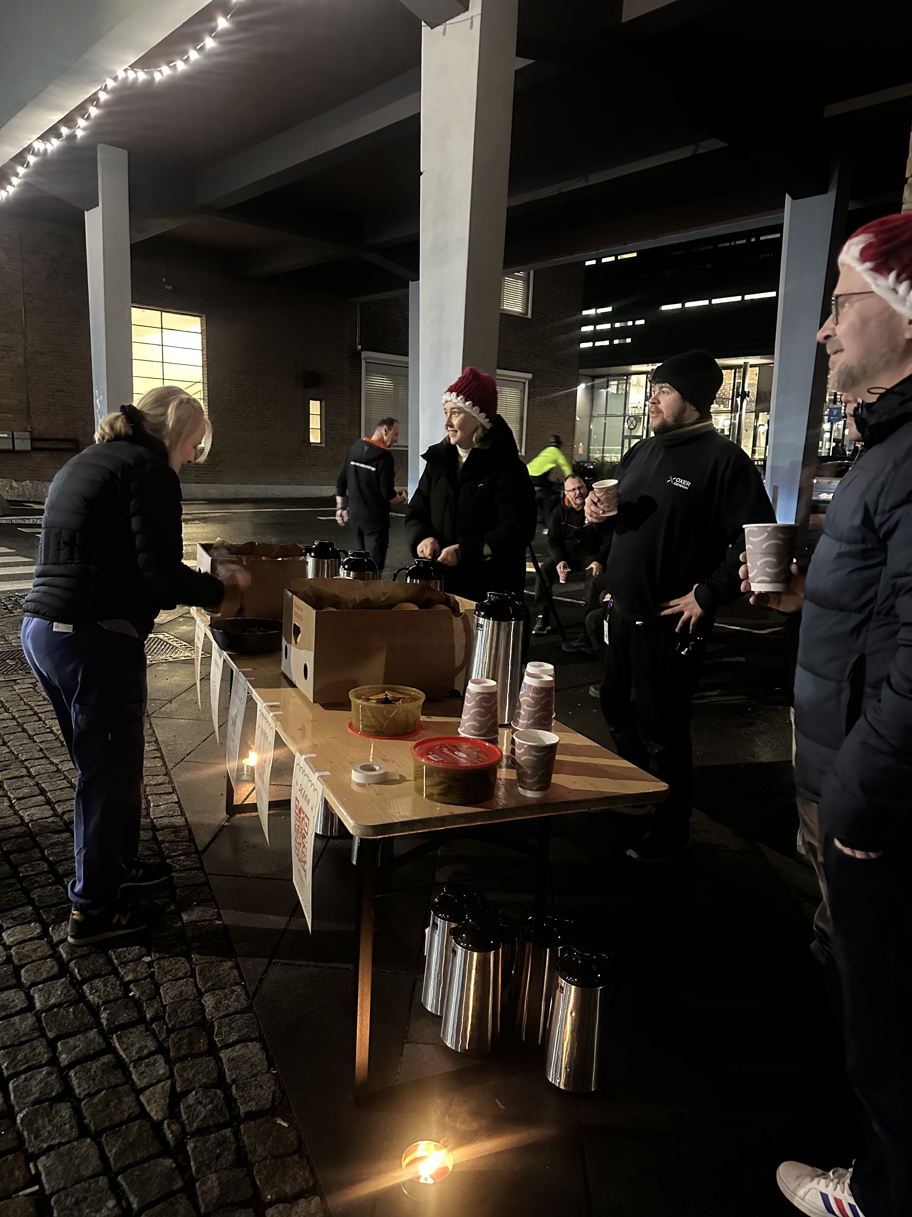Gløggservering under broen i lyskjedene en mørk morgen