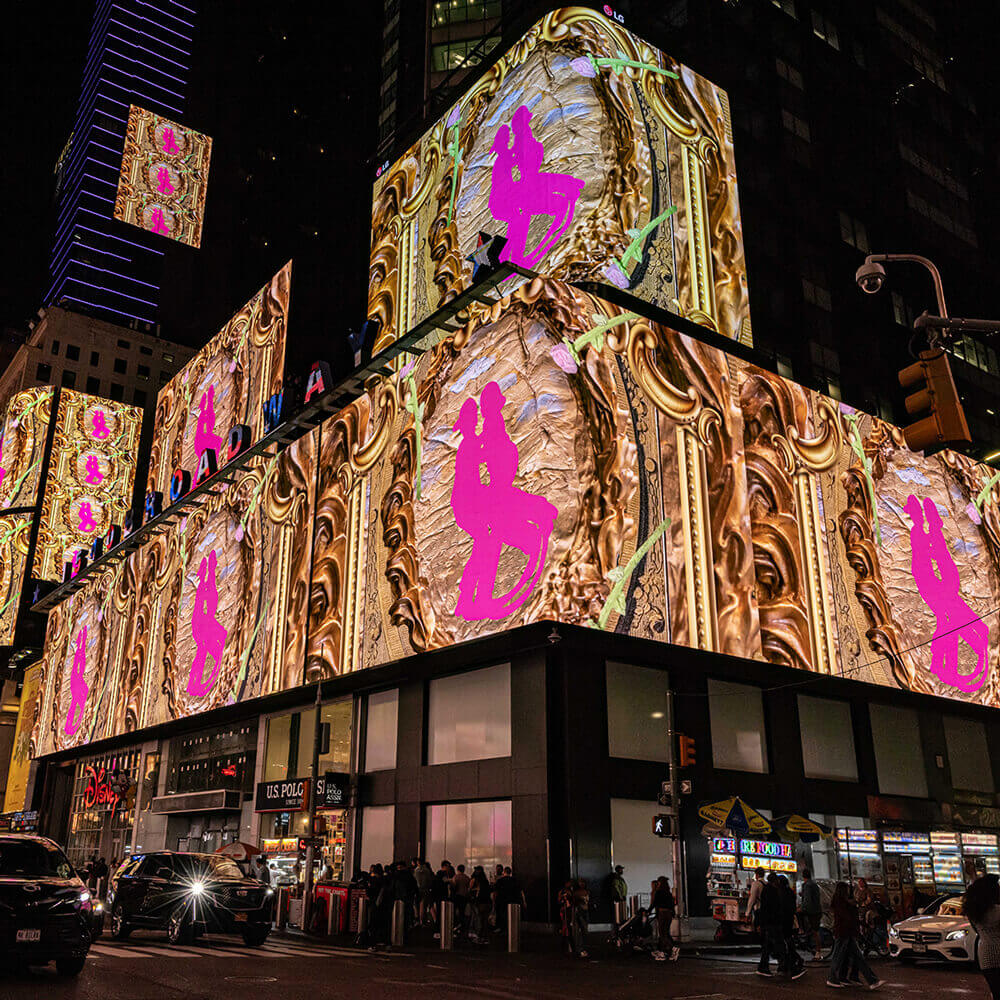 "PLEA$URE GARDEN$" by Yvette Mayorga on the screens of Times Square at midnight, showing an ornate gold background and a pink silhouette of two figures