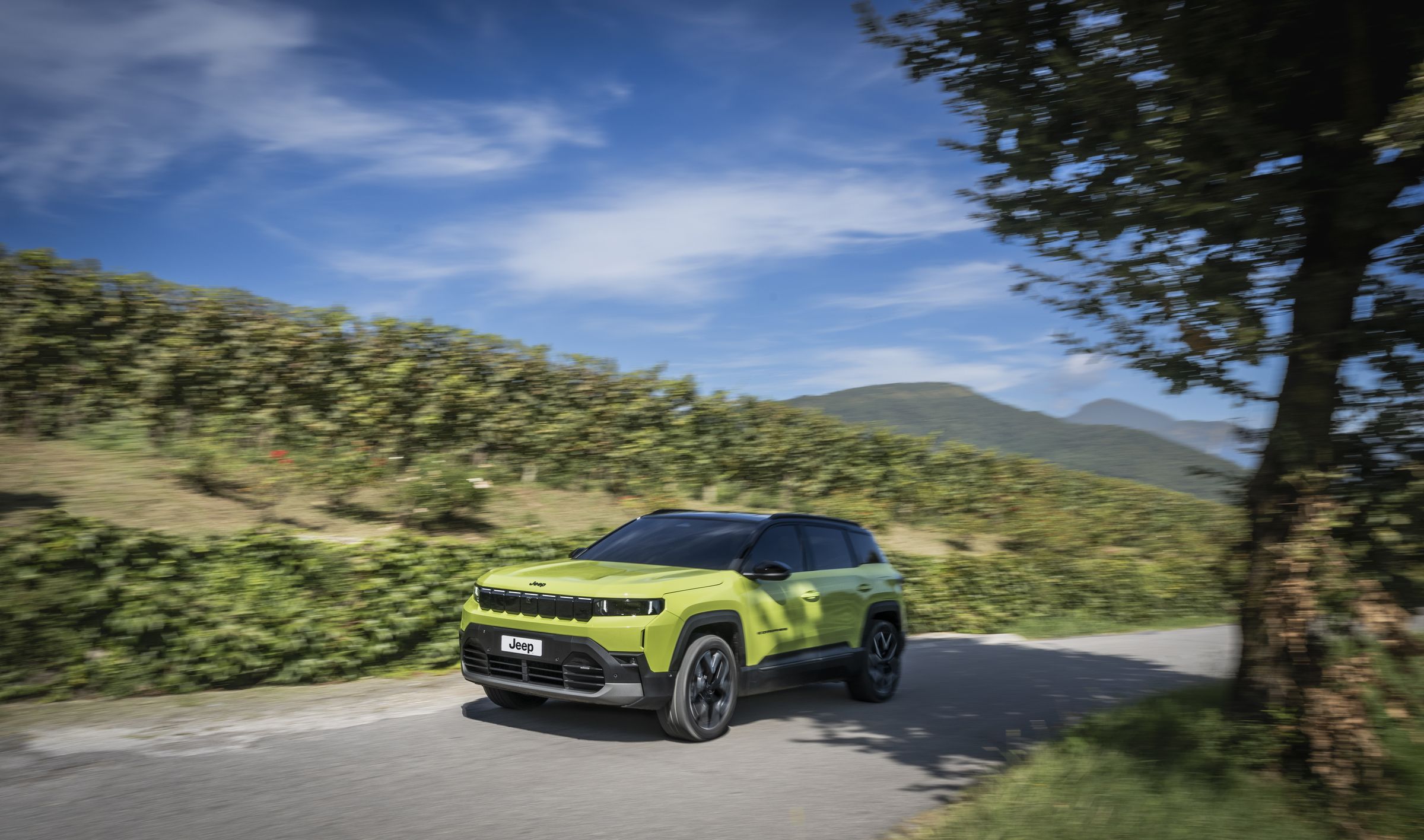 Neuer Jeep Compass e-Hybrid in Hawaii Grün fährt durch Weinberge, Dreiviertel-Frontansicht