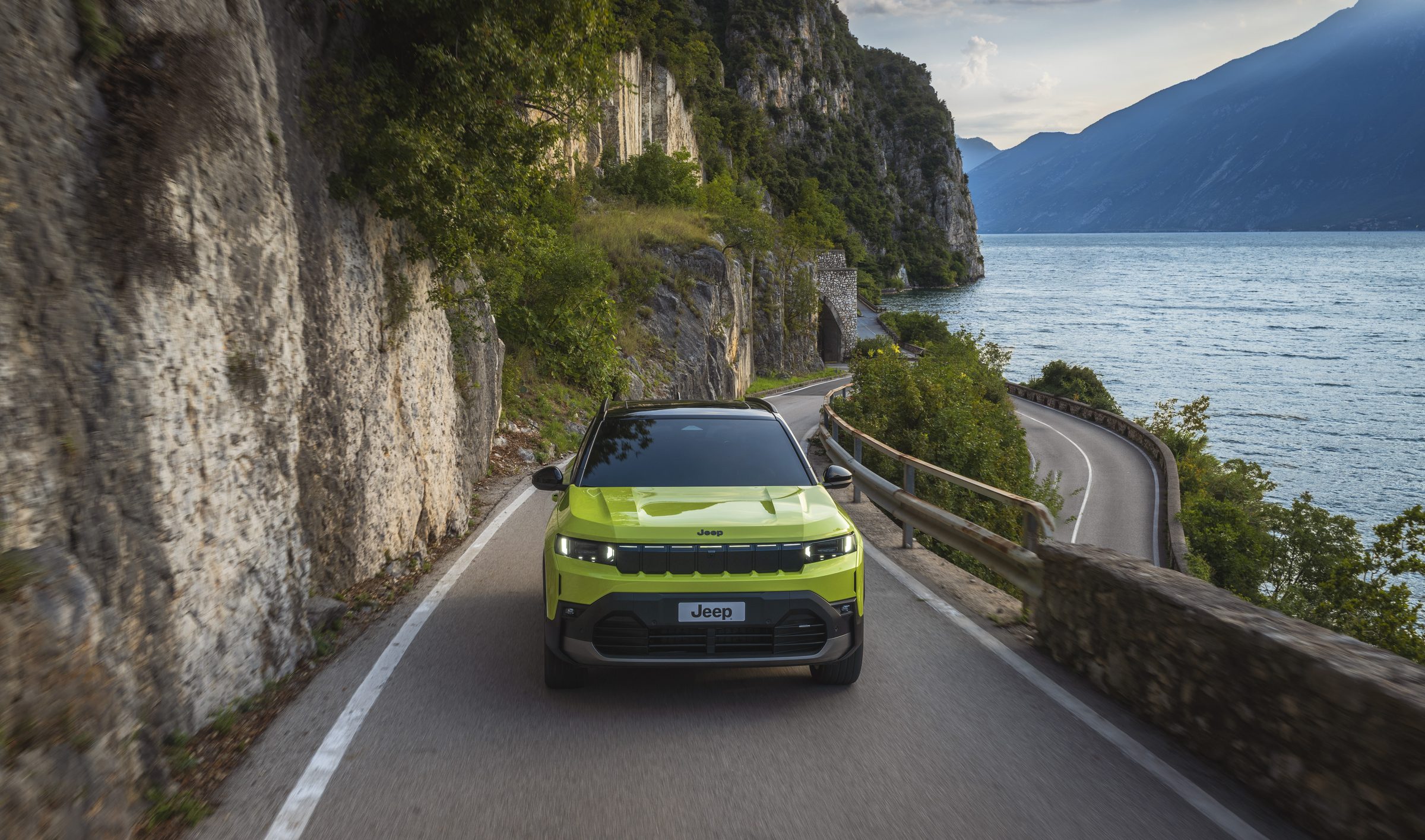Neuer Jeep Compass e-Hybrid in Hawaii Grün, Frontansicht auf einer Küstenstraße am See