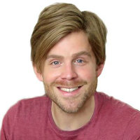 Michael is a white male in pink shirt smiling in a white background.