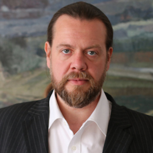 Alan Chamberlain is a white man with beard, in a grey background