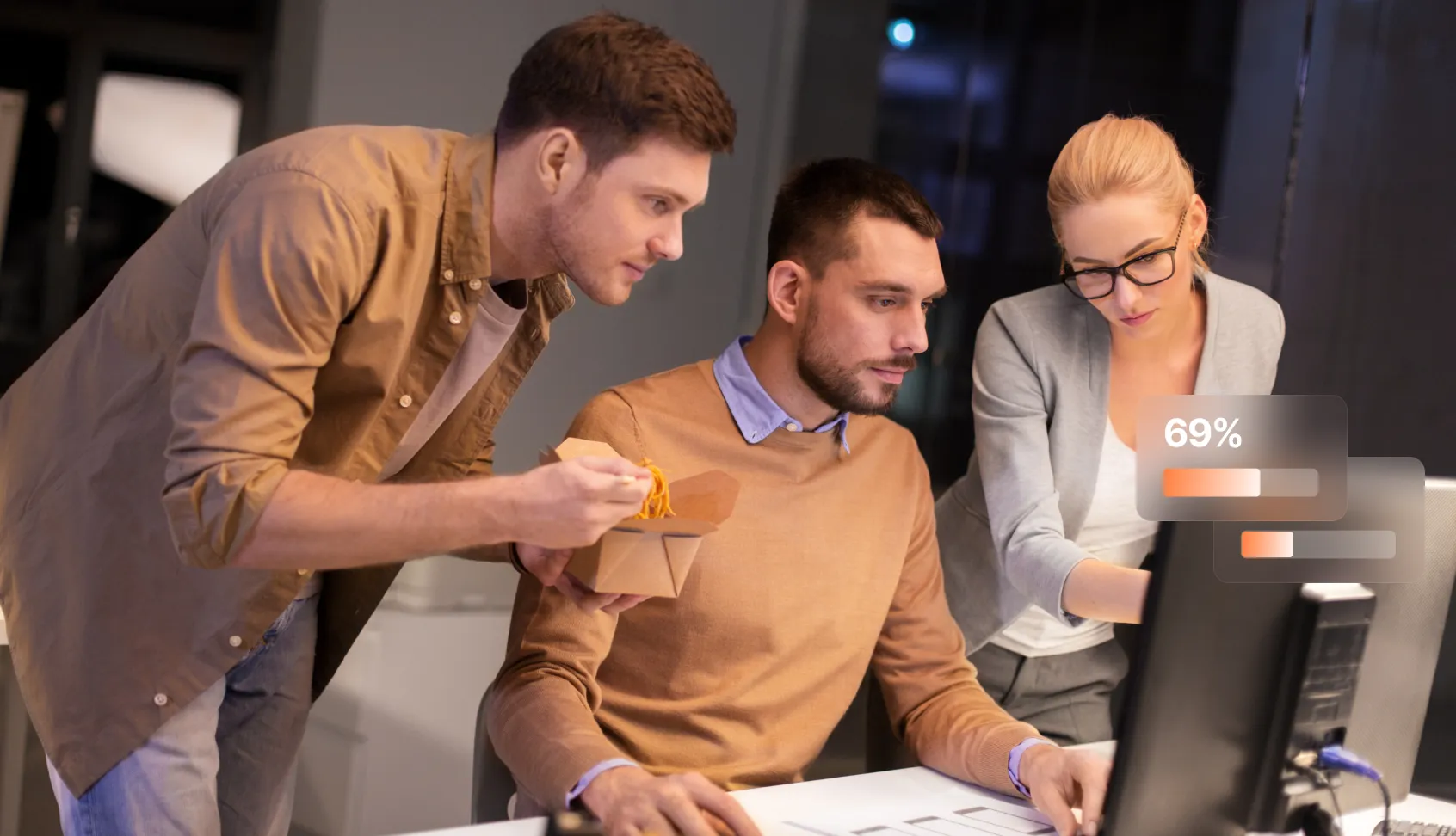 Three people collaborating at a desk with a computer