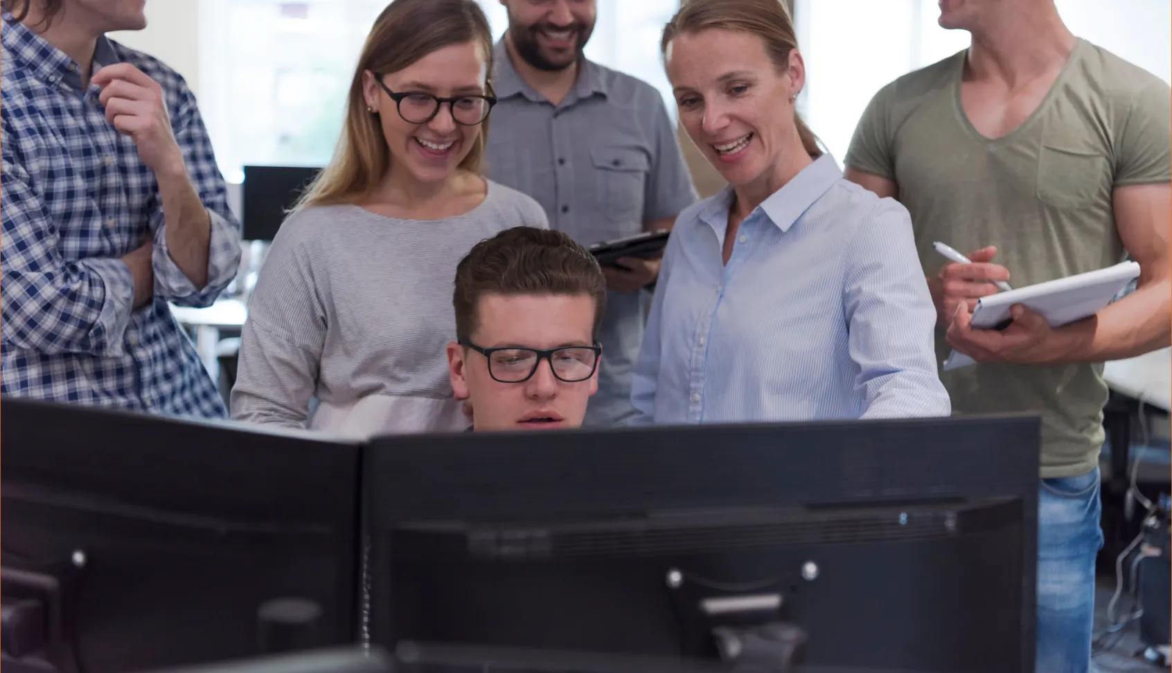 Group of people collaborating around computer monitors