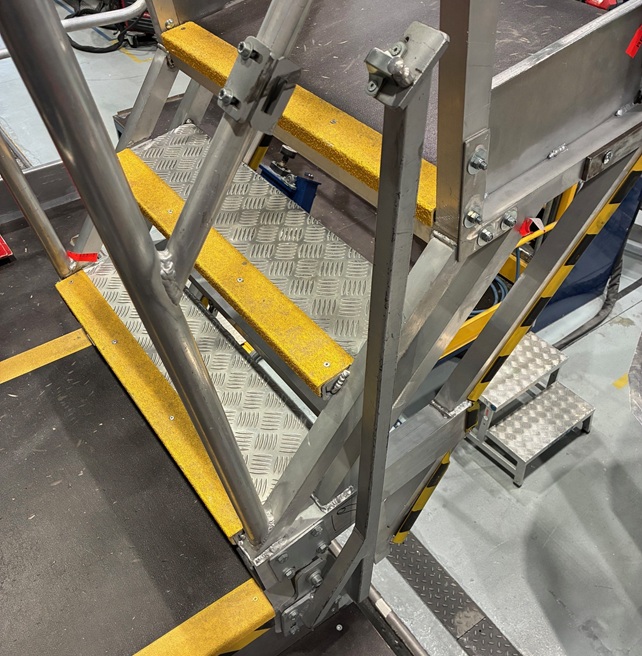 Passerelle mobile équipée d'un escalier pivotant industriel permettant un accès sécurisé aux zones de travail.
