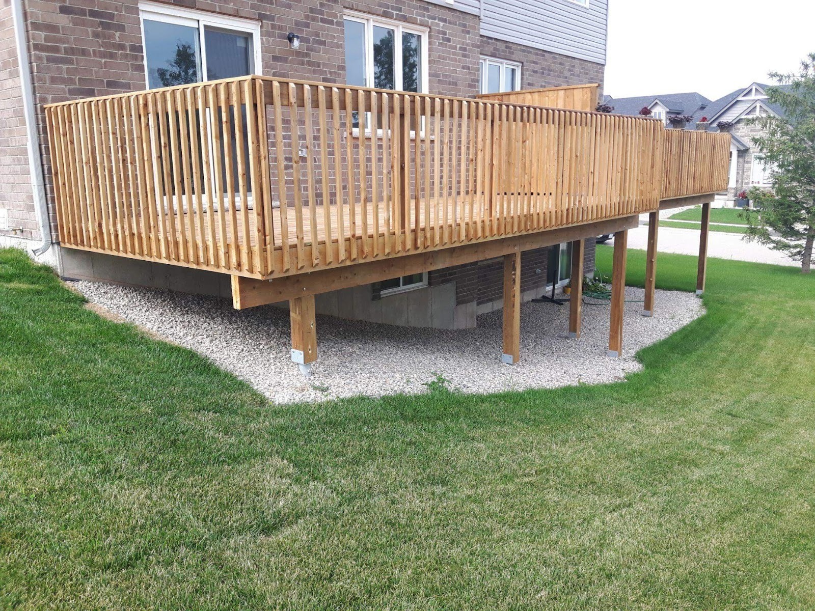Wooden deck on lawn near building with helical pile foundation