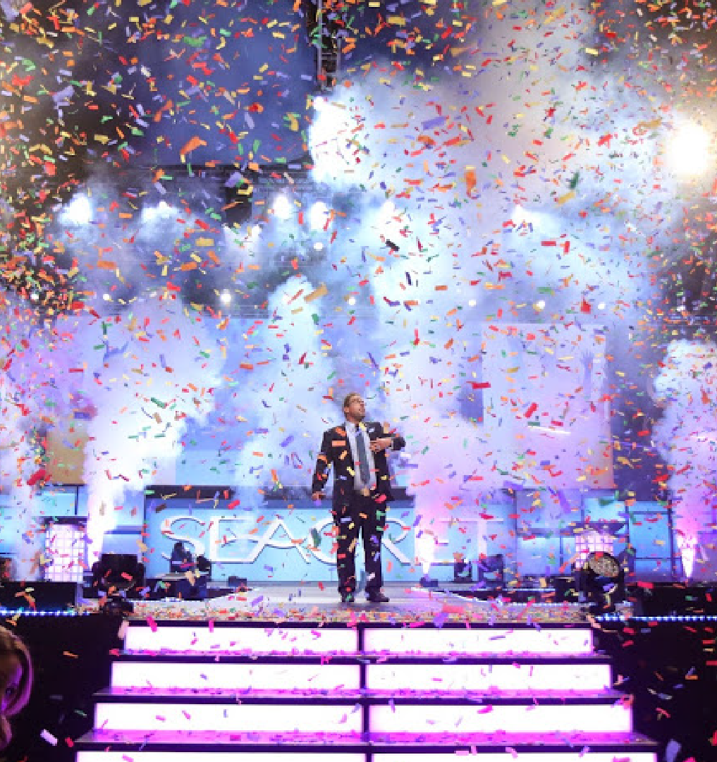 A speaker takes the stage amid Imprint's confetti effects at the Seacret Conference
