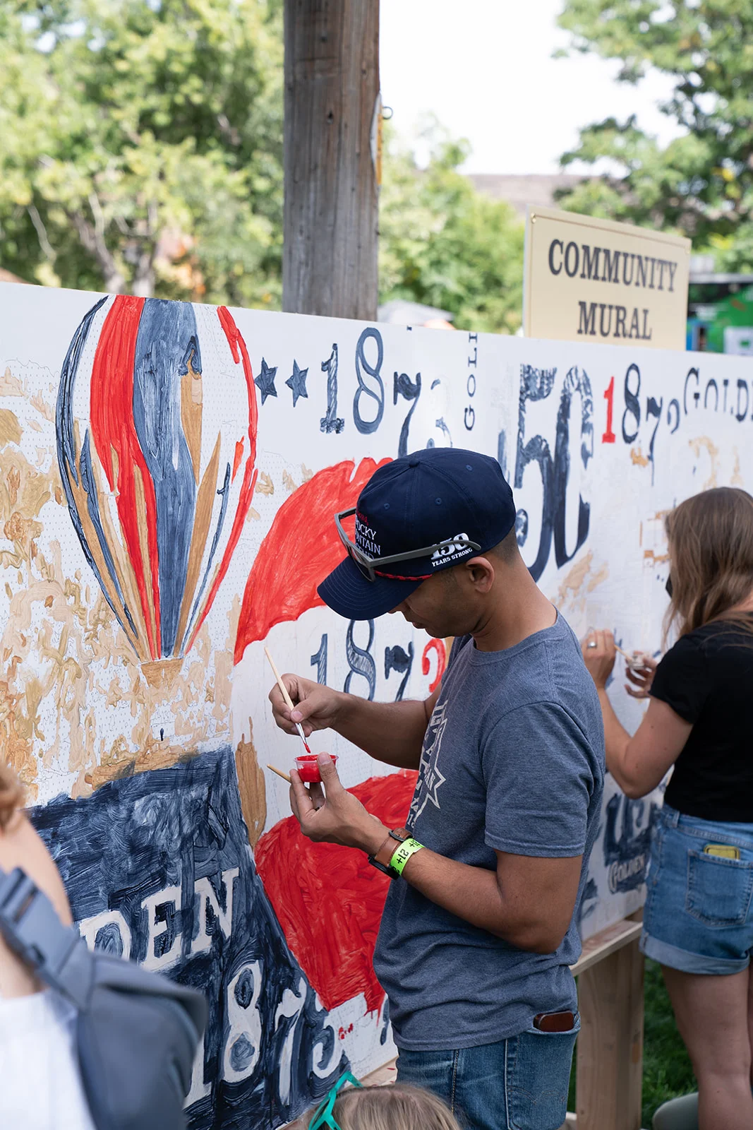 A guest paints Imprint's community mural activation at the Coors Brewery 150th Celebration
