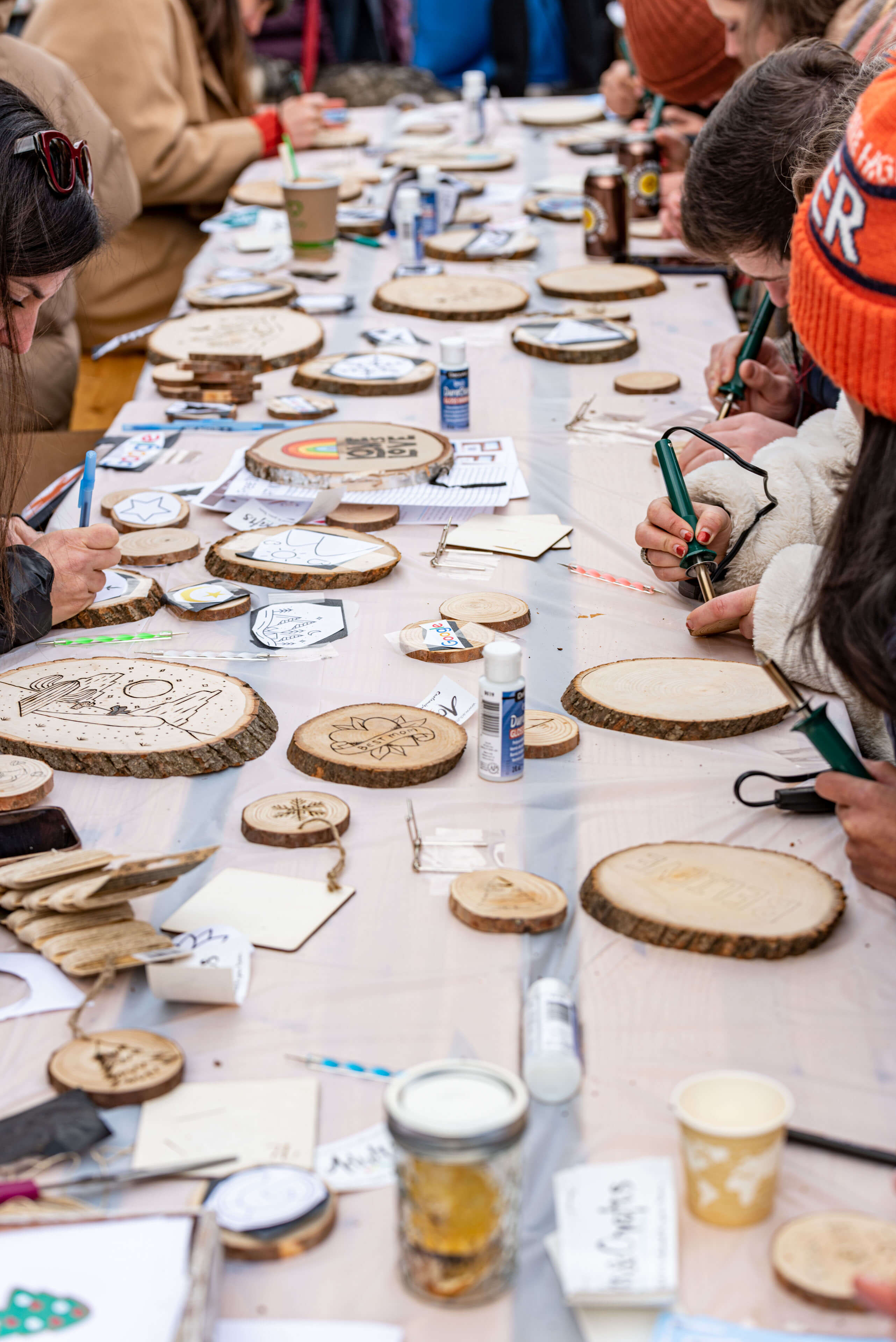 Guests try Imprint's wood-burning ornament activity at the Corporate Holiday Market