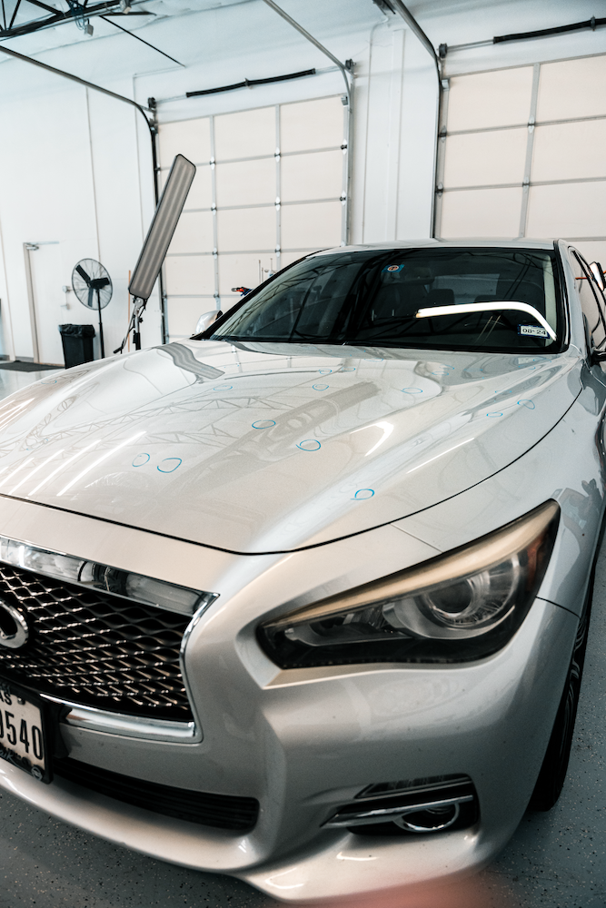 Technician using paintless dent repair tools to remove hail damage from a vehicle panel