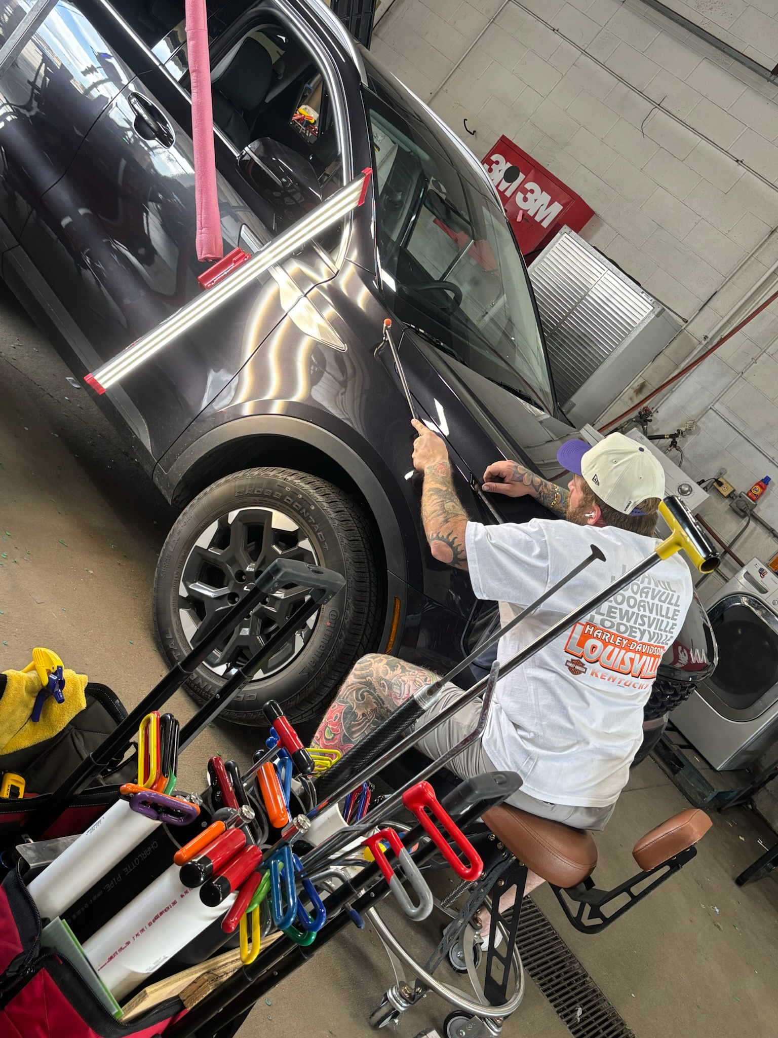Technician removing a tail light during vehicle disassembly for hail repair