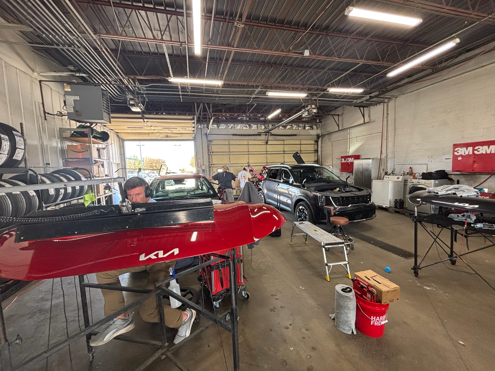 Interior of a hail repair facility with vehicles staged for paintless dent repair