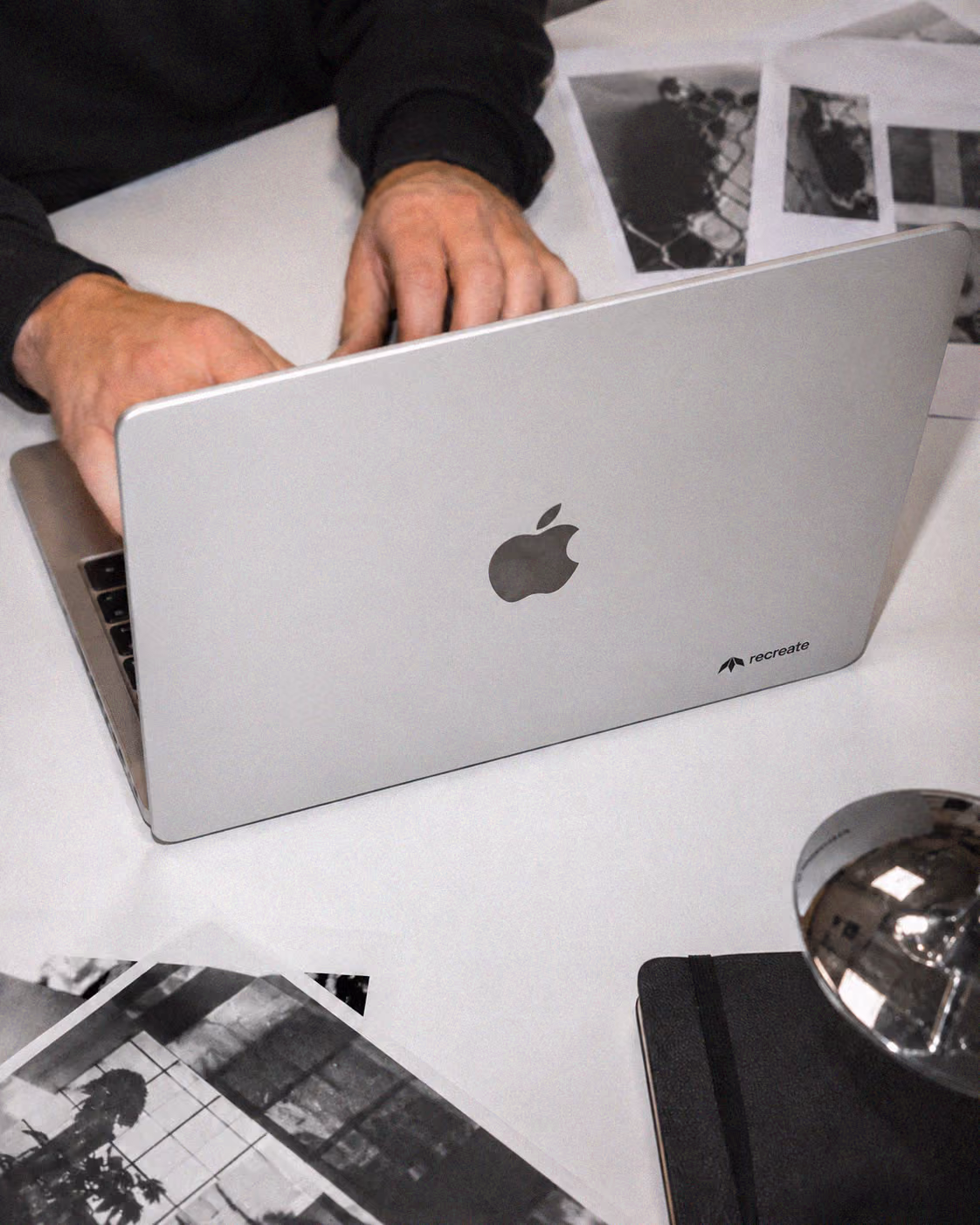 Recreate Webflow and graphic design studio in Wrocław working on a laptop with printed design references