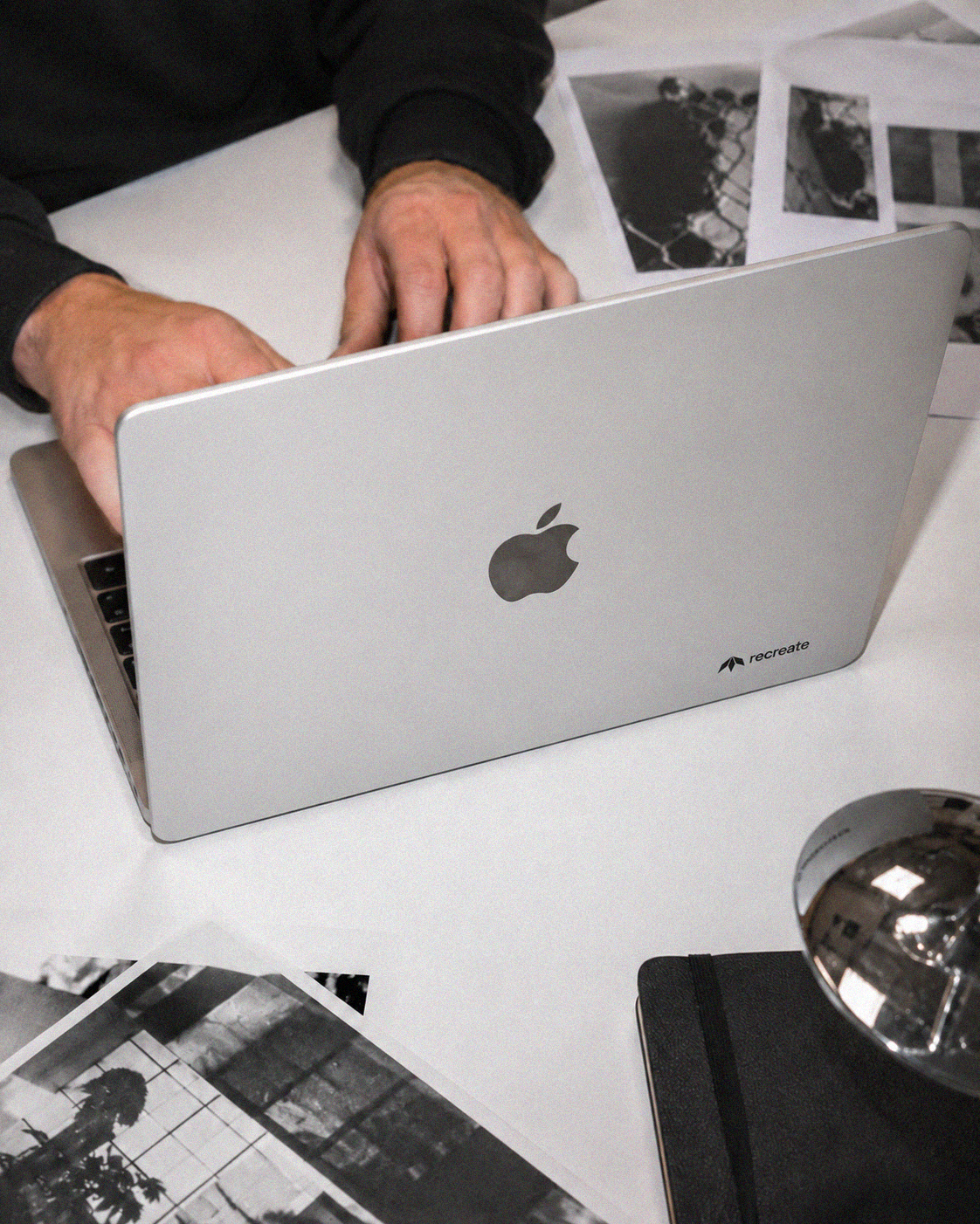 Recreate Webflow and graphic design studio in Wrocław working on a laptop with printed design references