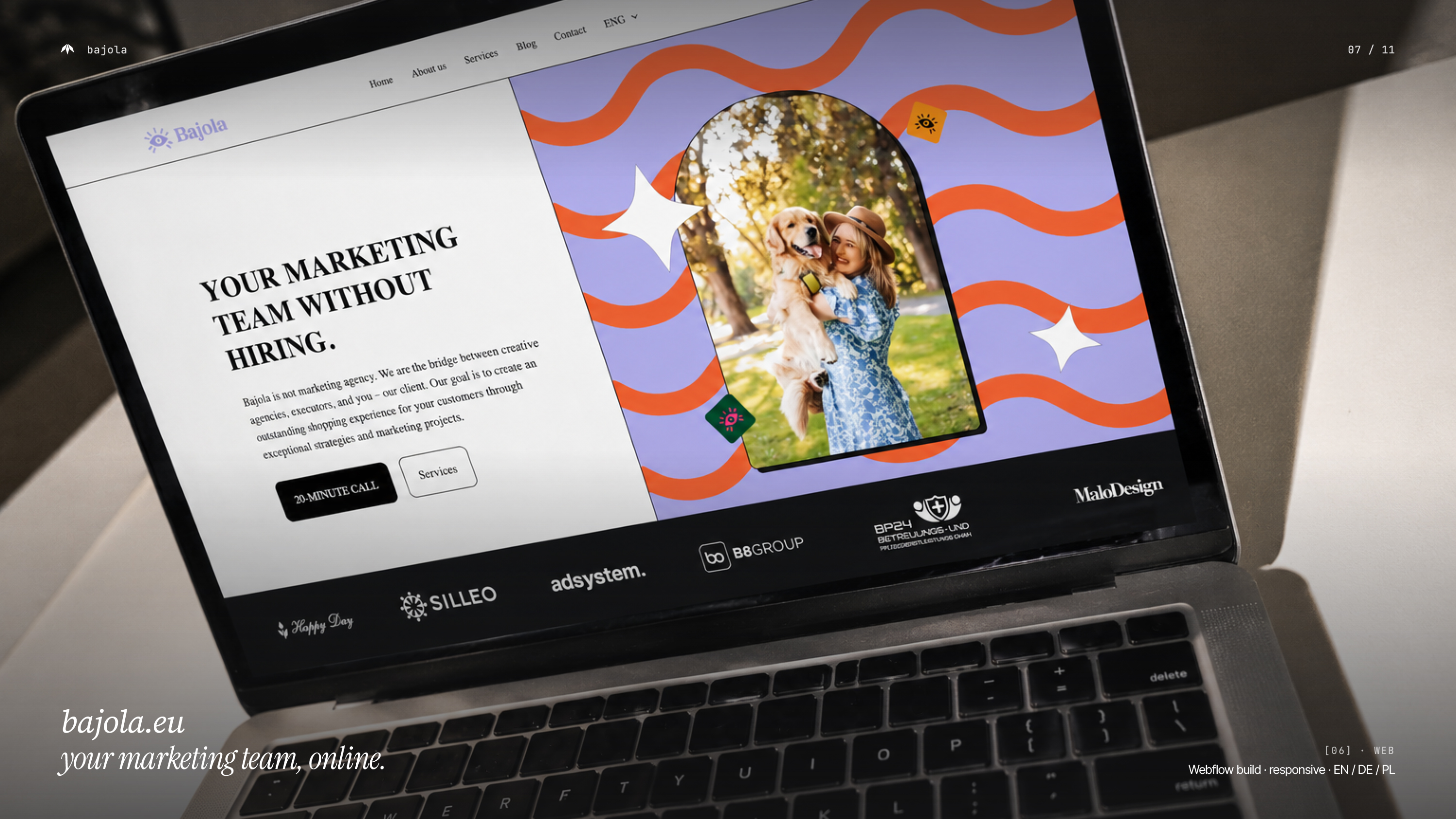 Bajola website homepage on a laptop, with a marketing services headline, a portrait and coral waves on a lavender background.
