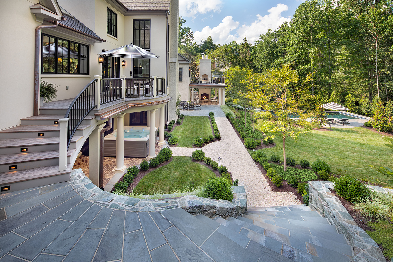 A beautiful stone stairway connects the upstairs deck to the downstairs areas, including a hot tub, fire pit and seating area, and the swimming pool.
