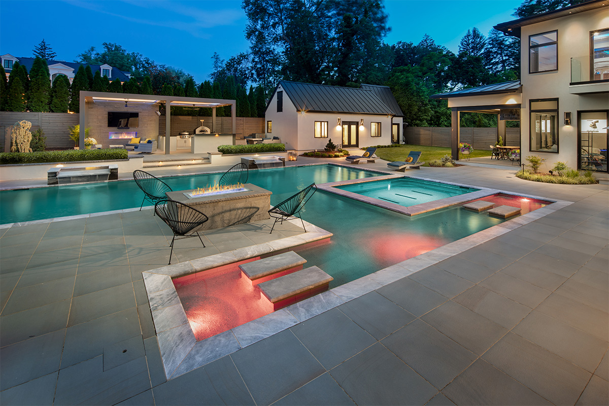 A gorgeous outdoor pool and retreat area at night, built by Rossen Landscape.