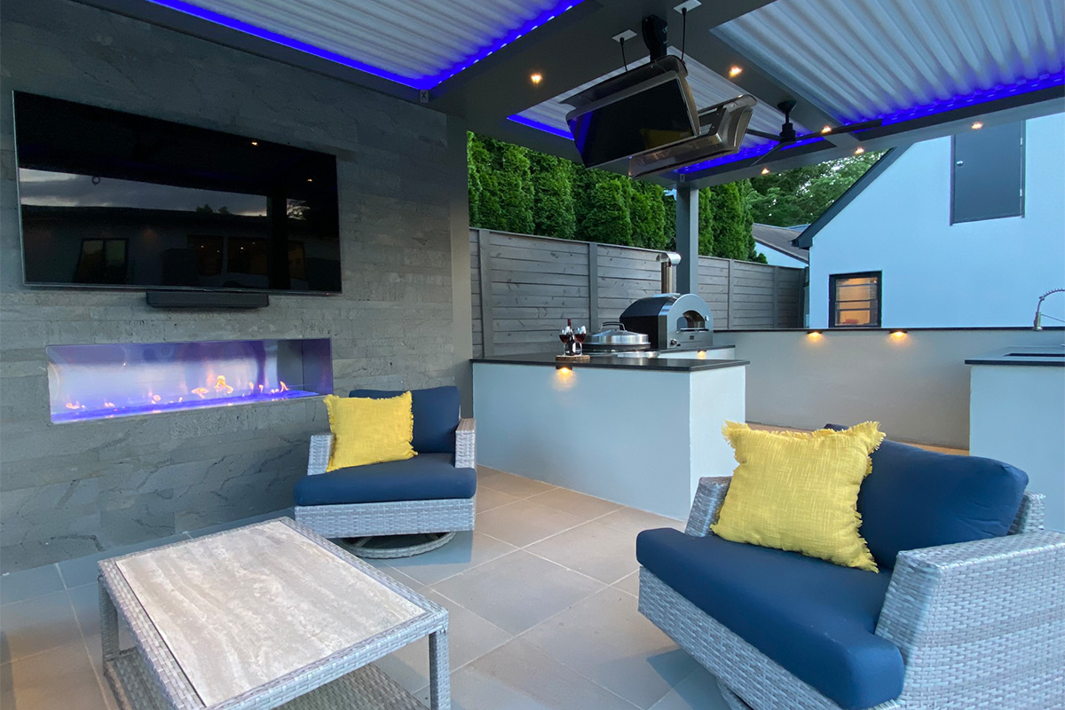 A custom pergola sits next to the swimming pool, complete with an outdoor kitchen, bar, TV, and fire features.