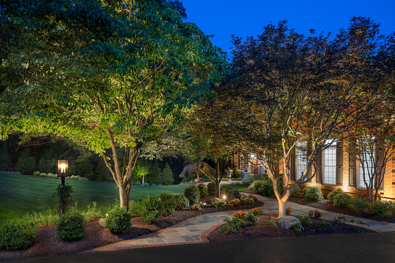 A beautiful landscape lit up with lighting around the walkway. This project was designed and built by Rossen Landscape.