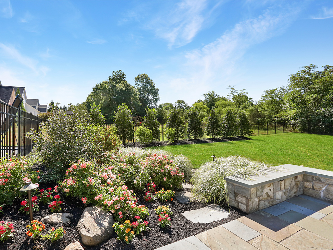 Gorgeous backyard retreat with stone patio, lounge chairs, brick wall, outdoor grill station, and luscious grass. This project was designed and built by Rossen Landscape.