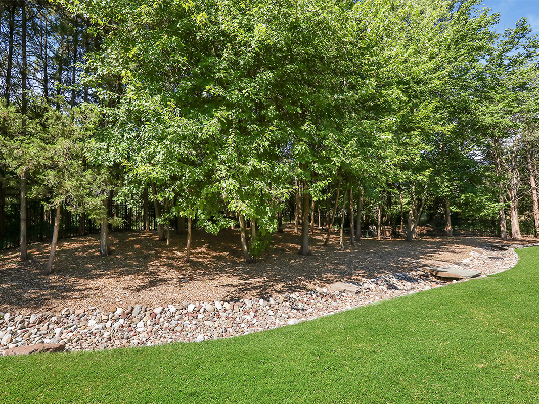 Gorgeous backyard retreat with stone patio, lounge chairs, brick wall, outdoor grill station, and luscious grass. This project was designed and built by Rossen Landscape.