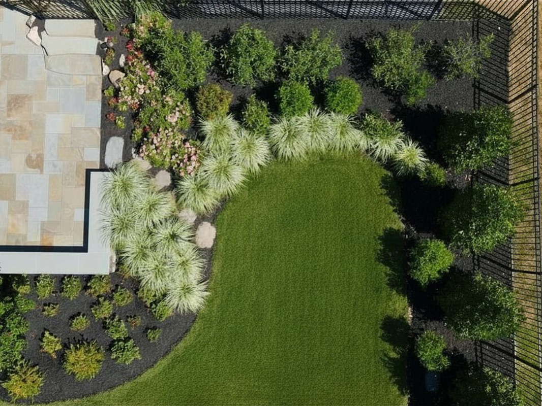 Gorgeous backyard retreat with stone patio, lounge chairs, brick wall, outdoor grill station, and luscious grass. This project was designed and built by Rossen Landscape.