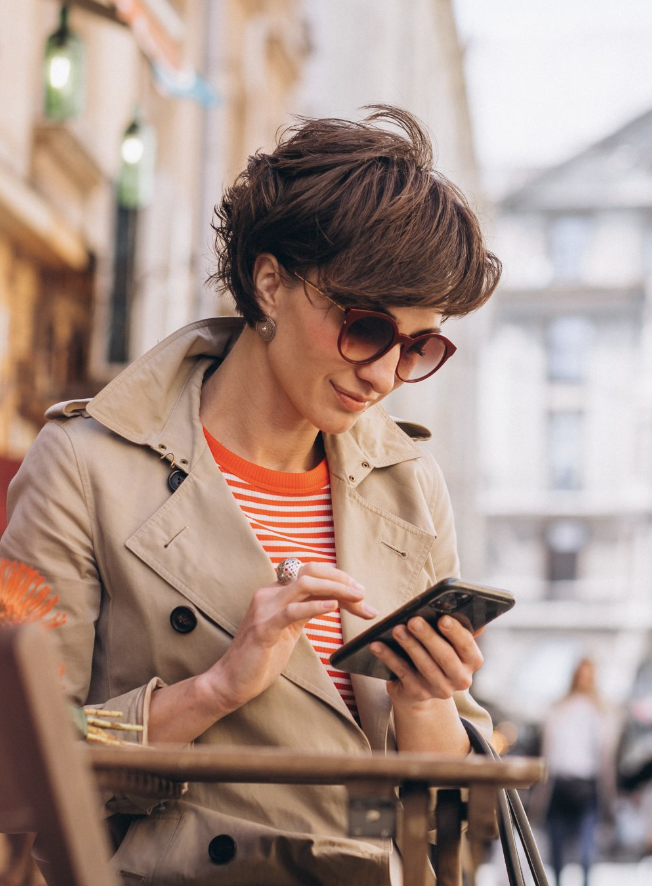 A woman with a pixie cut and sunglasses looking at her phone