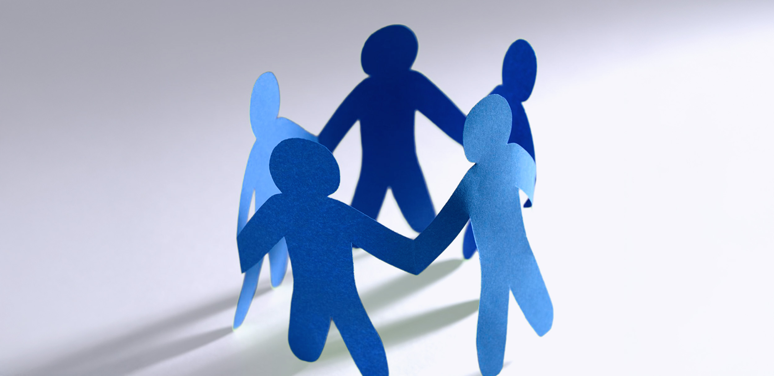 مجسمات ورقية لأشخاص يمسكون بأيدي بعضهم في دائرة ترمز إلى المشاركة المجتمعية، وتوضح مفهوم المشاركة المجتمعية وأهمية المشاركة المجتمعية في التعاون وصناعة التغيير.