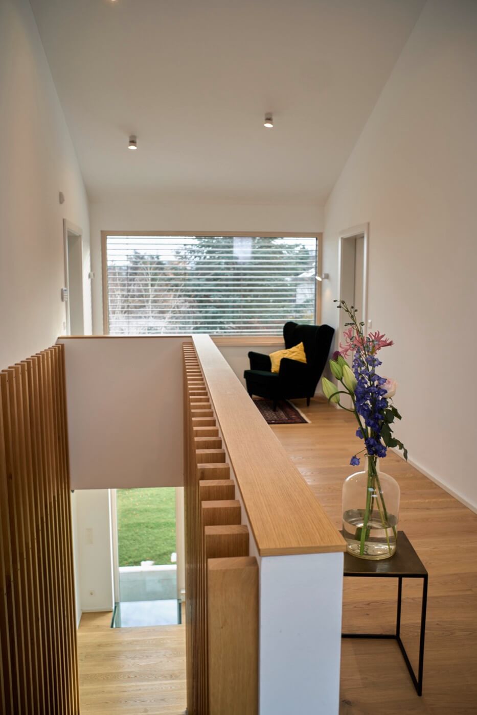 Galerie eines Fertigteilhauses, die durch helles Holz und minimalistisches Design besticht.