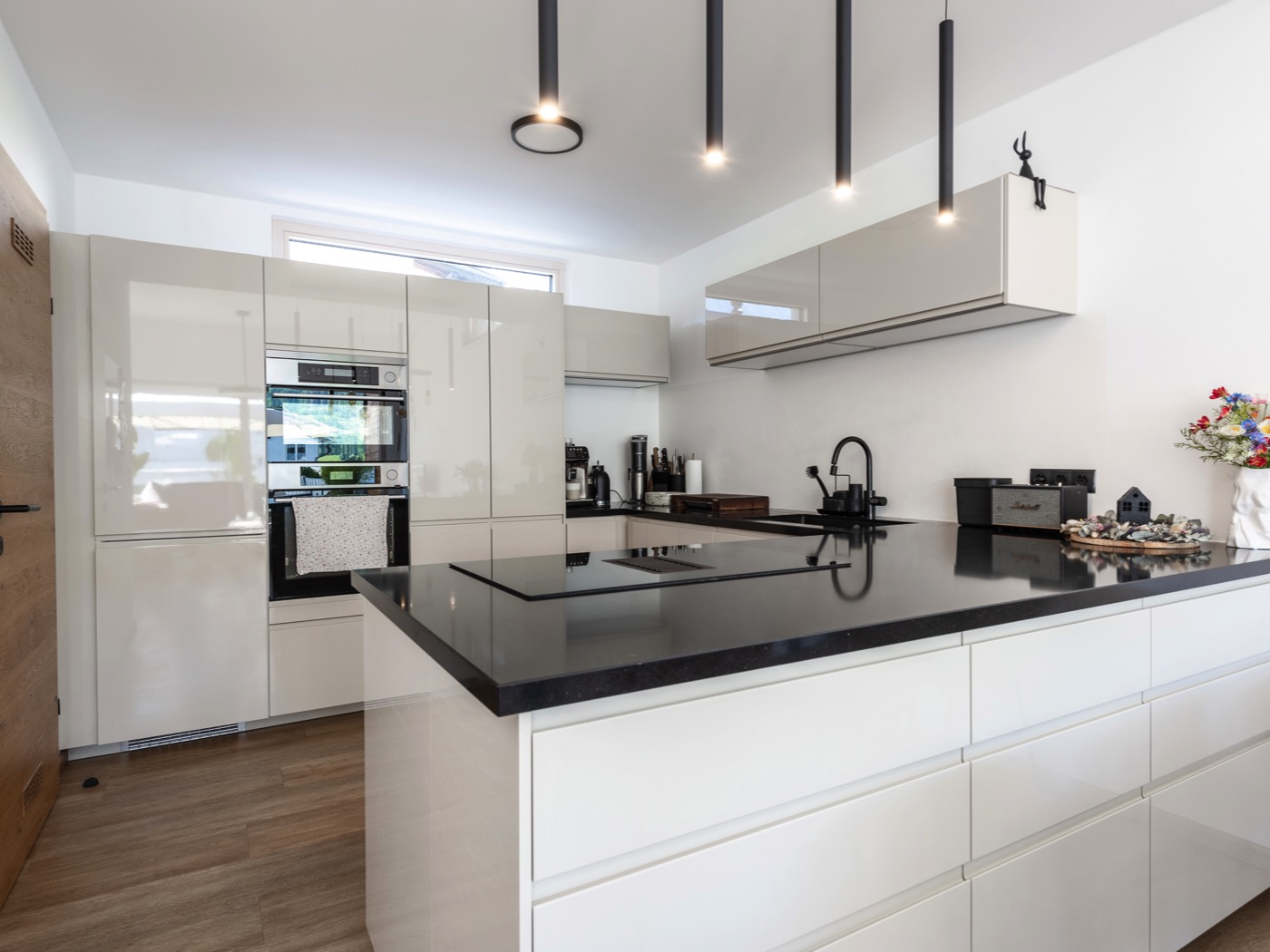 Einbauküche eines Fertigteilhauses in Hochglanzoptik mit einer Kücheninsel und integrierten Geräten.