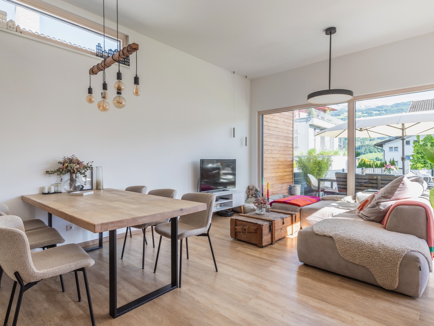 Wohn-Essbereich eines Fertigteuilhauses, dessen Einrichtung natürliche Materialien mit klaren Linien kombiniert.